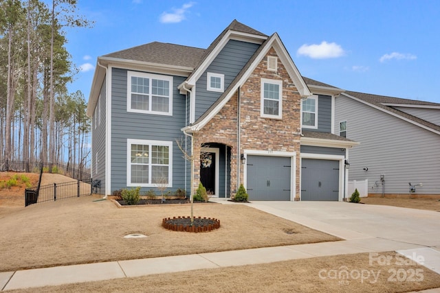 view of front facade featuring a shingled roof, concrete driveway, fence, a garage, and stone siding