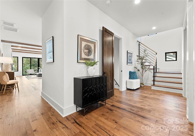 hallway featuring baseboards, stairway, hardwood / wood-style floors, and recessed lighting