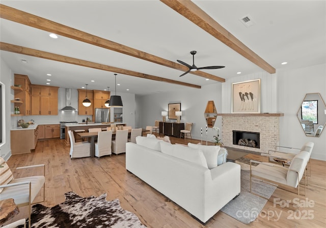 living room with recessed lighting, a fireplace, visible vents, light wood-style floors, and beamed ceiling