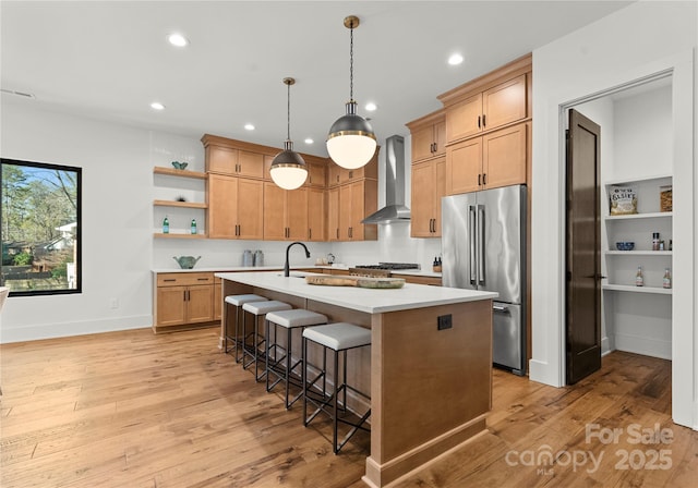 kitchen with open shelves, light countertops, appliances with stainless steel finishes, light wood-type flooring, and wall chimney exhaust hood