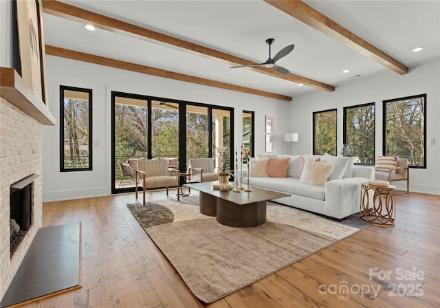 living area featuring baseboards, light wood-style flooring, beamed ceiling, french doors, and a fireplace