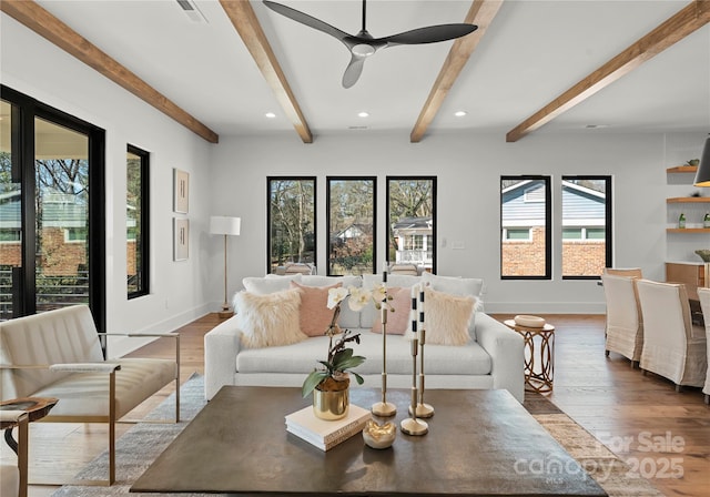 living room featuring beam ceiling, wood finished floors, visible vents, and baseboards