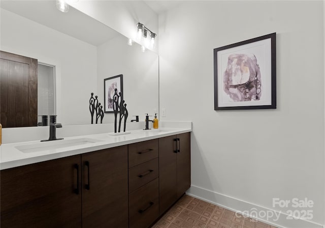 full bathroom with double vanity, a sink, and baseboards