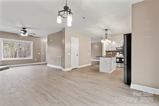 kitchen featuring pendant lighting, light hardwood / wood-style flooring, appliances with stainless steel finishes, tasteful backsplash, and white cabinets