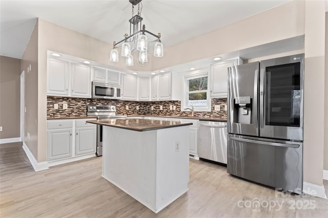 kitchen with pendant lighting, backsplash, white cabinets, and appliances with stainless steel finishes