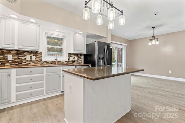 kitchen with stainless steel refrigerator with ice dispenser, sink, hanging light fixtures, and white cabinets