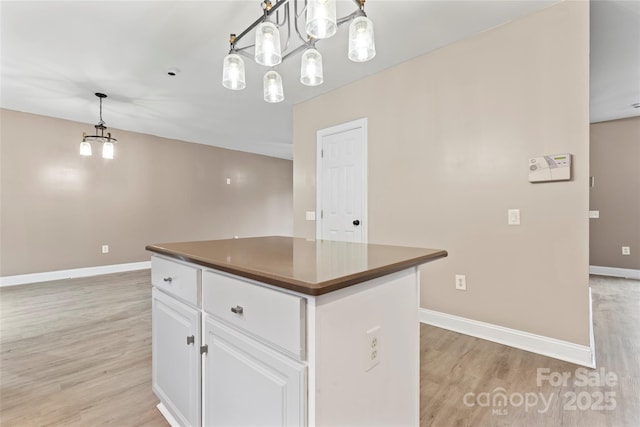 kitchen with decorative light fixtures, light hardwood / wood-style flooring, a center island, and white cabinets