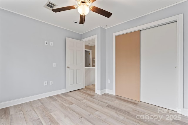 unfurnished bedroom with crown molding, a closet, ceiling fan, and light wood-type flooring