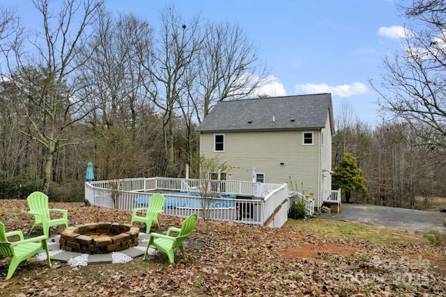 rear view of property with a covered pool and an outdoor fire pit