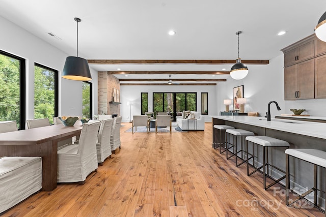kitchen with open floor plan, visible vents, a breakfast bar area, light wood finished floors, and a sink