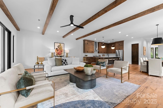 living area featuring ceiling fan, recessed lighting, light wood finished floors, baseboards, and beam ceiling