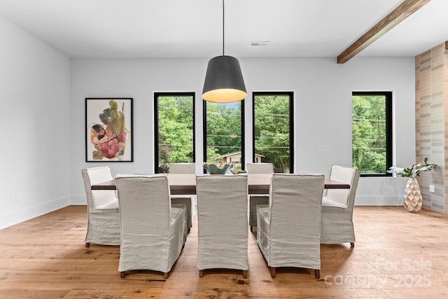 dining area with baseboards, visible vents, light wood-type flooring, and beamed ceiling