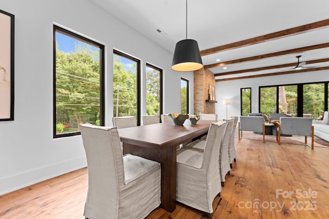 dining space with light wood finished floors, visible vents, baseboards, and beam ceiling