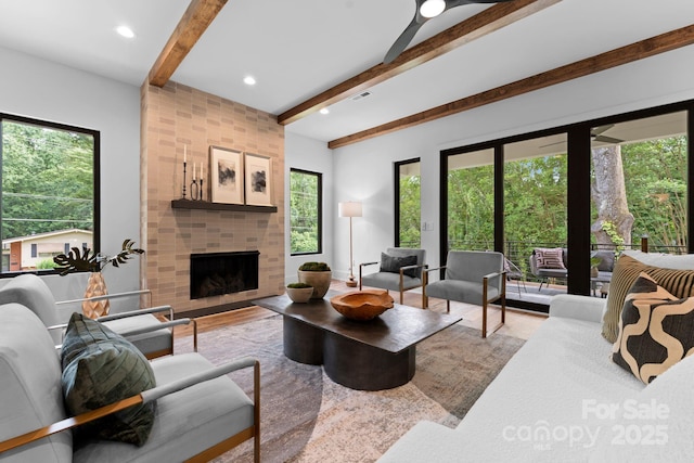 living area with plenty of natural light, a tile fireplace, visible vents, and beam ceiling