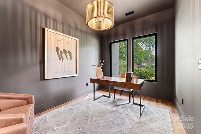 home office featuring visible vents, baseboards, an inviting chandelier, and wood finished floors