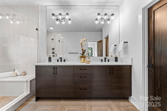 full bathroom with a tile shower, double vanity, a sink, and tile walls