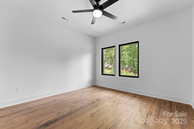 empty room with visible vents, baseboards, hardwood / wood-style floors, and a ceiling fan