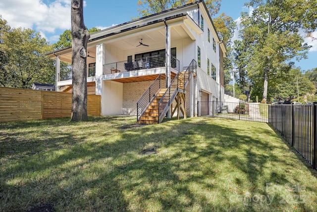 back of property with stairway, a fenced backyard, a ceiling fan, and a lawn
