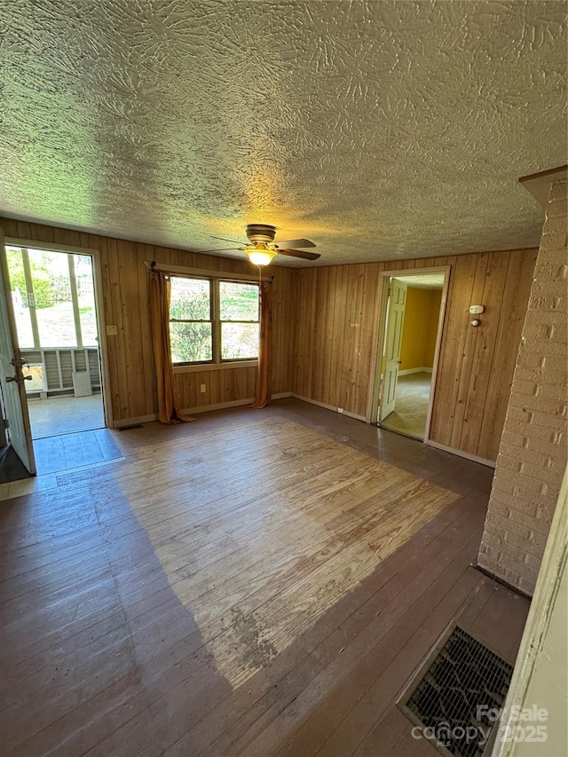 17 Jenny St, Asheville, NC 28806 - unfurnished living room with hardwood / wood-style flooring, a ceiling fan, wood walls, baseboards, and a textured ceiling