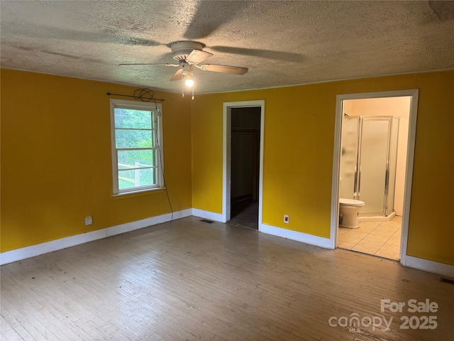 17 Jenny St, Asheville, NC 28806 - unfurnished bedroom featuring wood-type flooring, baseboards, a textured ceiling, a spacious closet, and connected bathroom