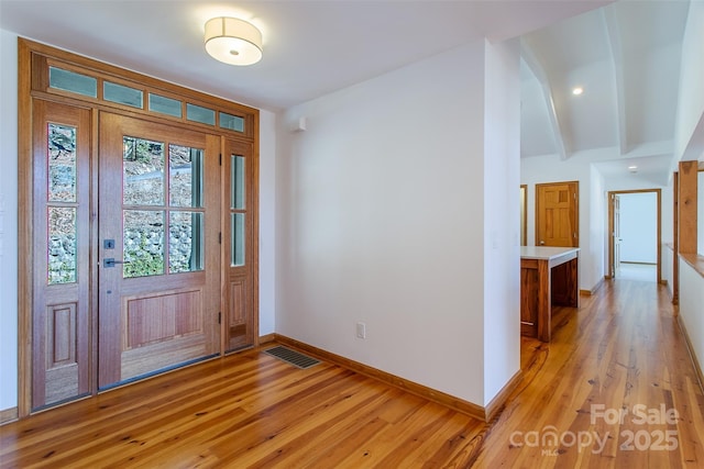 entrance foyer with light wood-style flooring, baseboards, beamed ceiling, and visible vents