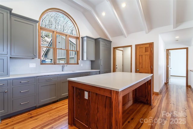 kitchen featuring lofted ceiling with beams, light countertops, and gray cabinetry