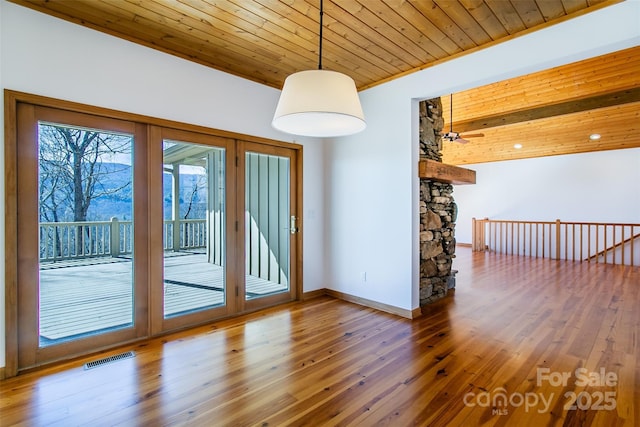 empty room featuring wooden ceiling, baseboards, wood finished floors, and visible vents