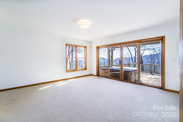 carpeted empty room with a mountain view, baseboards, and visible vents