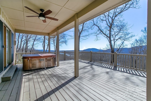 deck with a ceiling fan, a mountain view, and a hot tub