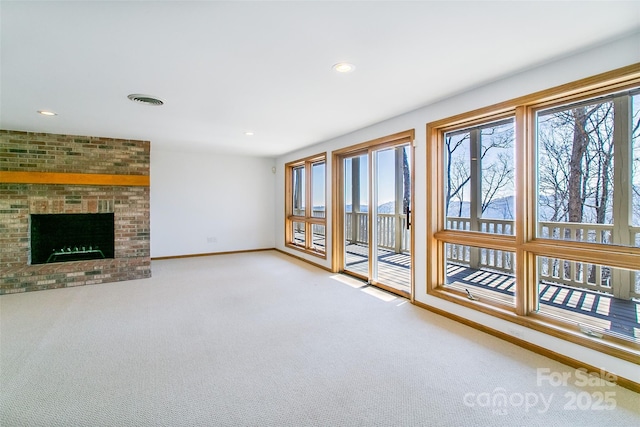 unfurnished living room with carpet floors, baseboards, visible vents, and a wealth of natural light