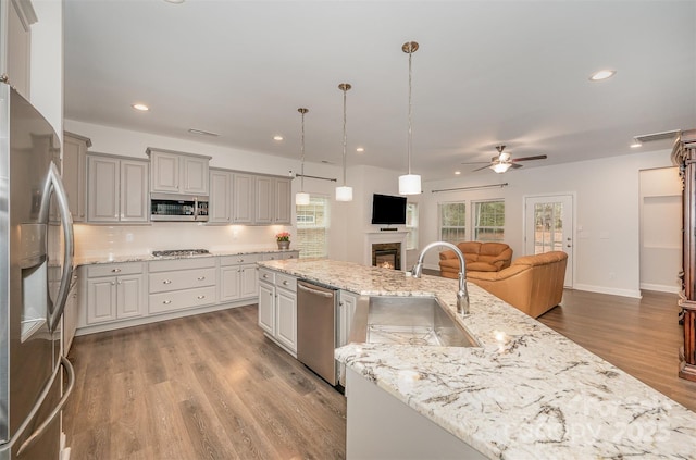 kitchen featuring pendant lighting, sink, gray cabinets, a kitchen island with sink, and stainless steel appliances