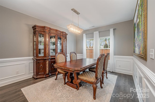 dining space with dark hardwood / wood-style flooring and a chandelier