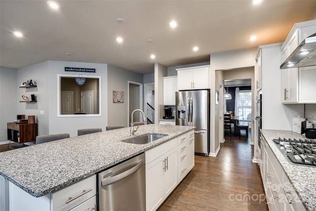 kitchen with a center island with sink, appliances with stainless steel finishes, dark wood-type flooring, white cabinetry, and a sink