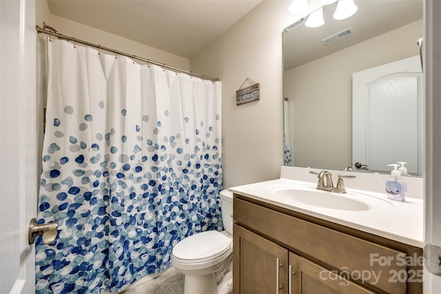 bathroom with toilet, vanity, and visible vents