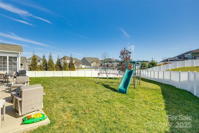 view of yard with a fenced backyard, a residential view, and a playground