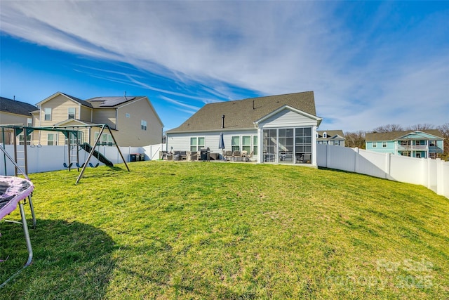 rear view of house with a residential view, a sunroom, a fenced backyard, and a lawn