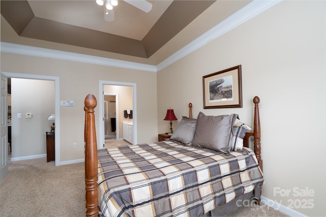 bedroom featuring connected bathroom, a tray ceiling, ornamental molding, ceiling fan, and light carpet