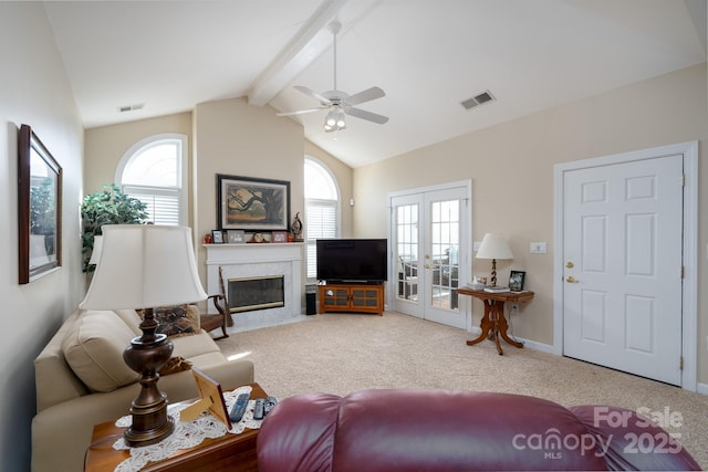 carpeted living room with a fireplace, french doors, lofted ceiling with beams, and a healthy amount of sunlight