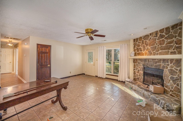 unfurnished living room with a fireplace, light tile patterned floors, a textured ceiling, and ceiling fan