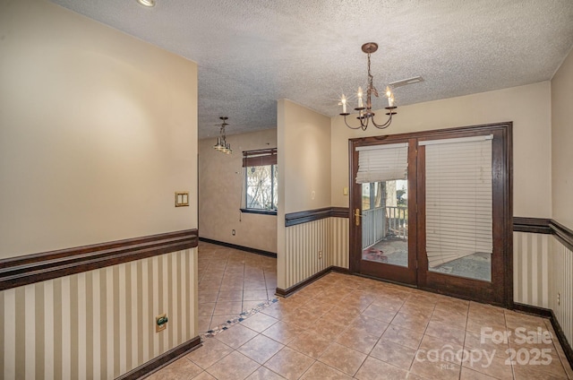 interior space with tile patterned floors, a chandelier, and a textured ceiling