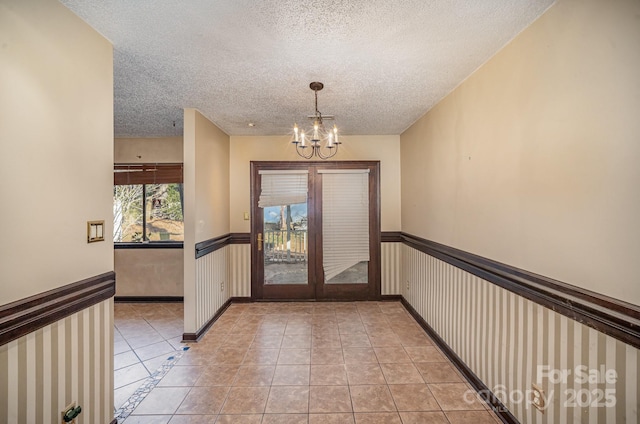 doorway featuring a notable chandelier, light tile patterned floors, french doors, and a textured ceiling