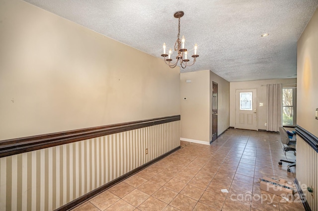 entryway featuring light tile patterned floors, a chandelier, and a textured ceiling