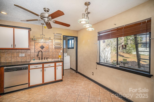 kitchen with white cabinetry, sink, stainless steel dishwasher, and washer / dryer