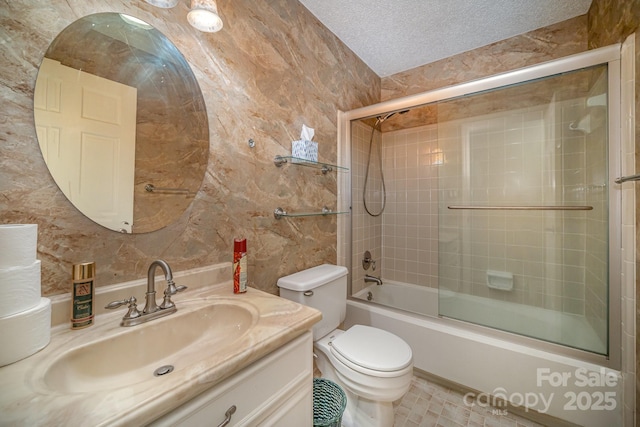 full bathroom with a textured ceiling, toilet, vanity, and combined bath / shower with glass door