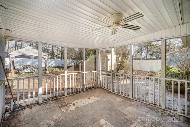 unfurnished sunroom featuring ceiling fan and plenty of natural light