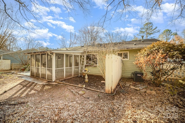 rear view of property with central air condition unit and a sunroom