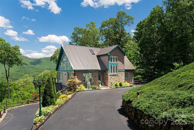 chalet / cabin with stone siding, metal roof, a mountain view, and aphalt driveway