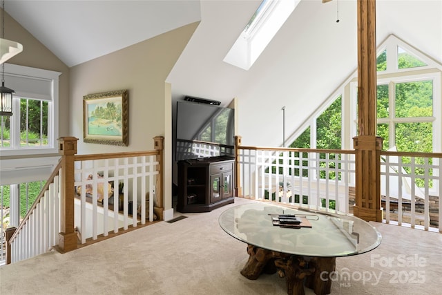 sitting room with carpet floors, lofted ceiling with skylight, and an upstairs landing