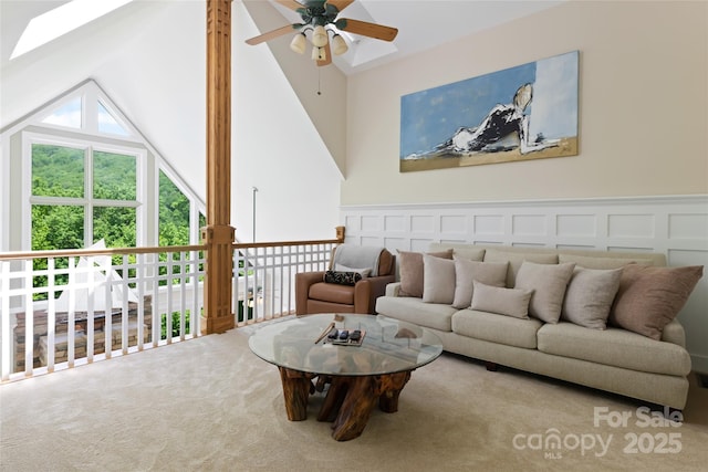 living area with lofted ceiling, a wainscoted wall, ceiling fan, carpet flooring, and a decorative wall