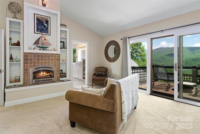 carpeted living room featuring lofted ceiling, a mountain view, a fireplace, built in features, and baseboards